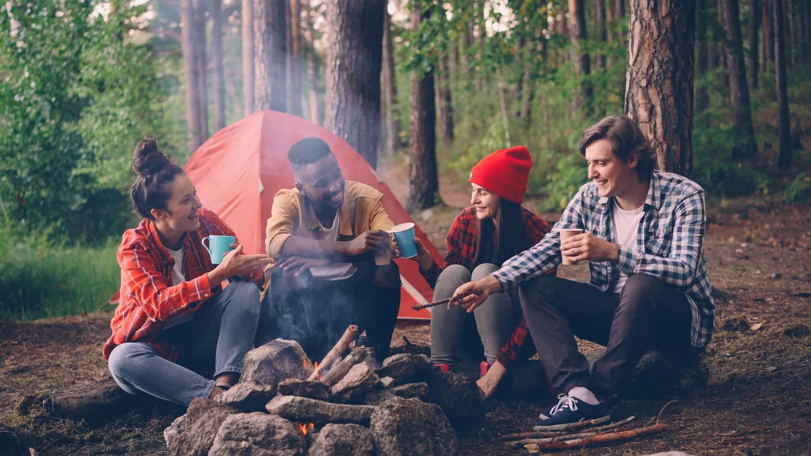Group of friends relaxing by campfire in forest, camping in nature.